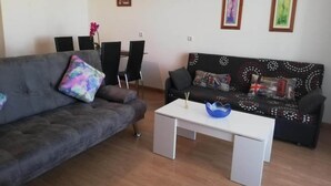 A living room with a grey sofa, a patterned sofa, a white coffee table, and a dining area with chairs and a table. - Perfect Getaway in Vera With Terrace (Vera)