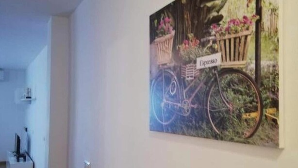 A hallway with a wall-mounted painting of a bicycle with a basket and flowers, and a red flag. - Perfect Getaway in Vera With Terrace (Vera)