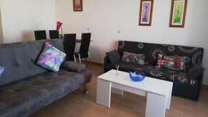 A living room with a grey sofa, a patterned sofa, a white coffee table, and a dining area with chairs and a table. - Perfect Getaway in Vera With Terrace (Vera)