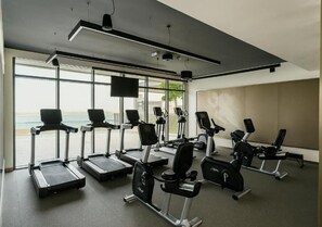 A gym with treadmills, elliptical machines, and weight stations. - Palm View Flat at Beachvista (Dubai)