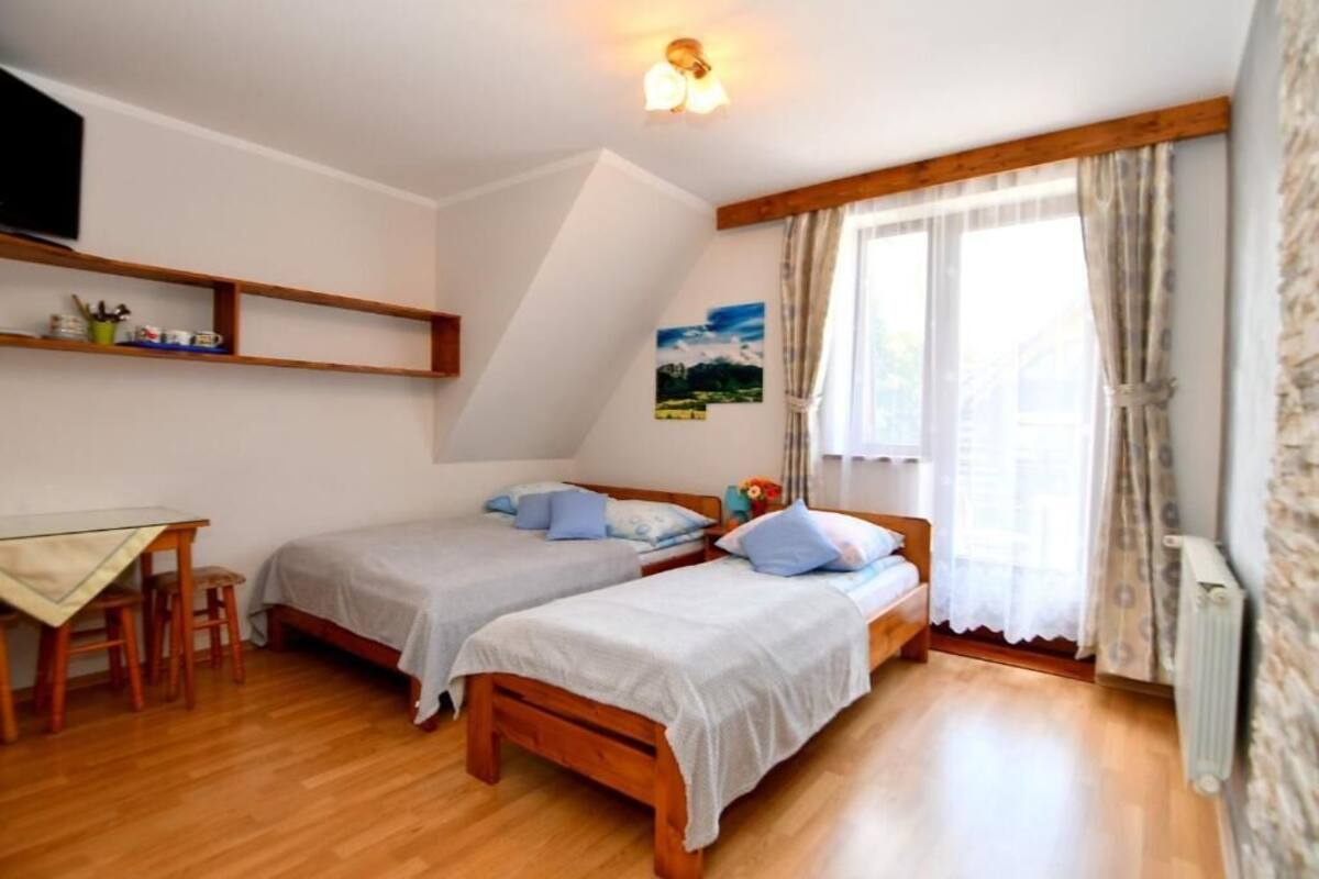 Una habitación con dos camas individuales, un escritorio de madera y una silla.