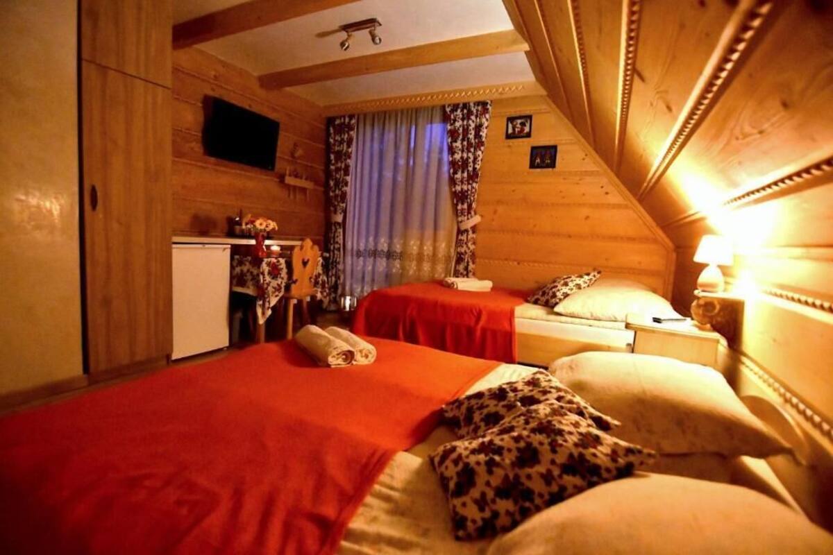 Una habitación acogedora con dos camas, un escritorio pequeño y una televisión.