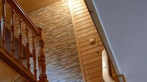 A wooden staircase with a stone wall and a light fixture. - Pokoje Gościnne Majerczyk  (Zakopane)
