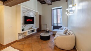Ein Wohnzimmer mit Fernseher, Sofa, Couchtisch und einem Fenster mit Blick.