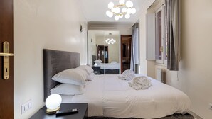 Ein Hotelzimmer mit Bett, Nachttisch, Lampe und Blick auf den Flur.