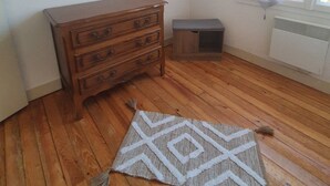 A room with wooden flooring, a wooden dresser, a small bench, a window with sheer curtains, and a painting on the wall. - Vacation home on the Bay of Arcachon (La Teste-de-Buch)