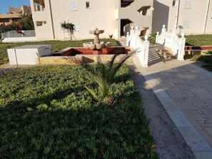 A landscaped area with a fountain, a pathway, and a building with balconies. - Perfect Getaway in Vera (Vera)