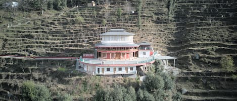 A multi-story building with a central tower, surrounded by terraced fields.
