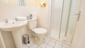 Een badkamer met een wastafel, toilet en douchecabine met glazen wanden.