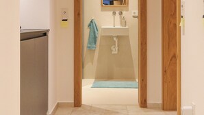 A hallway leading to a bathroom with a mirror, sink, and towel rack.