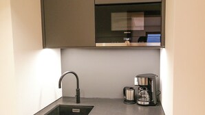 A kitchen with a sink, a coffee maker, and a microwave.