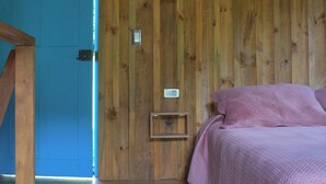 Une pièce en bois avec un lit, une porte bleue et une petite table de chevet.
