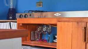 Une cuisine de taille réduite avec un mur bleu, une cuisinière en acier inoxydable, un mixeur et un réfrigérateur.