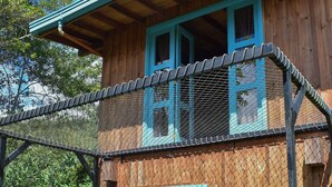Une maison en bois à deux étages, dotée d’un balcon, d’une porte bleue et d’un petit porche.