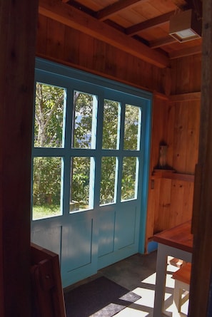 Une pièce avec une grande porte bleue, des murs en bois et une petite table.