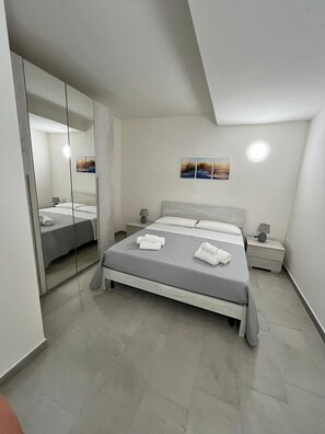 Ein modernes Schlafzimmer mit einem Bett, Nachttischen, einem Spiegel und Bildern an der Wand.