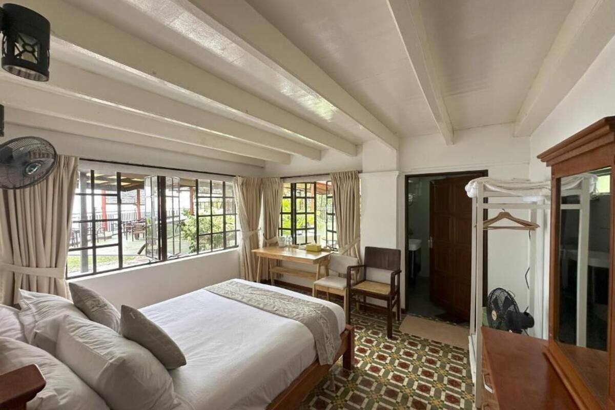 Une chambre d’hôtel avec un grand lit, un bureau, une chaise et une armoire.