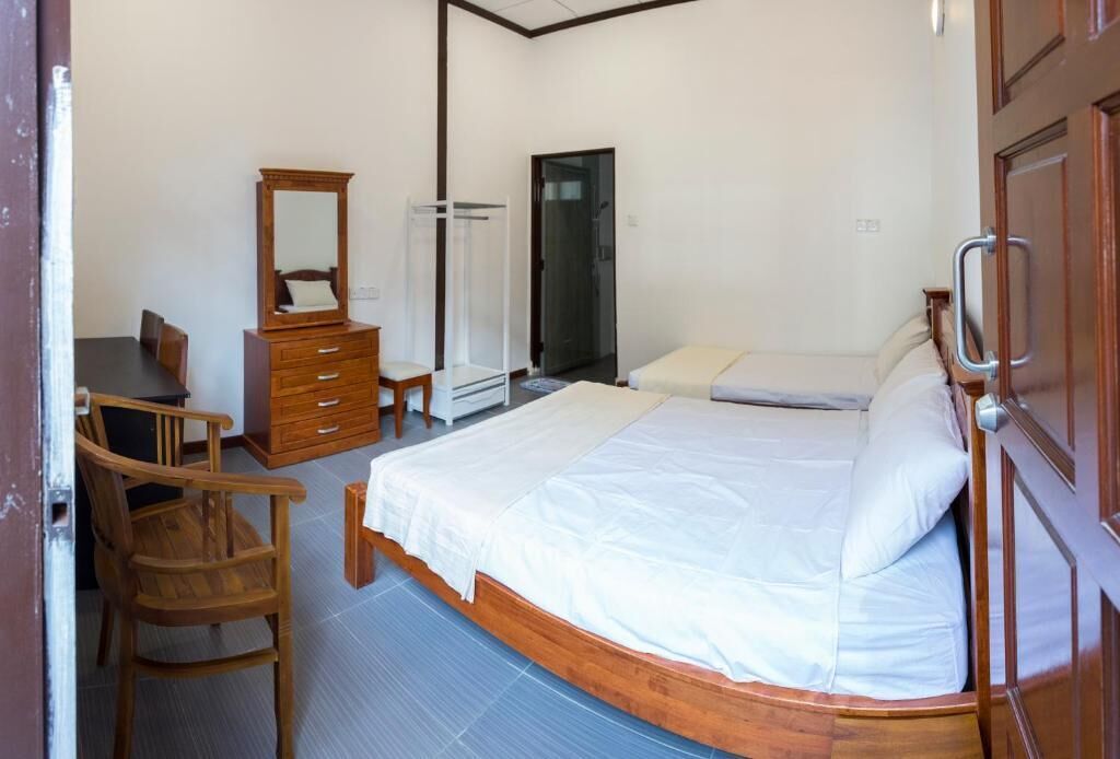 Ein Schlafzimmer mit einem Bett, einem Holzkleiderschrank, einem Stuhl und einer Tür.