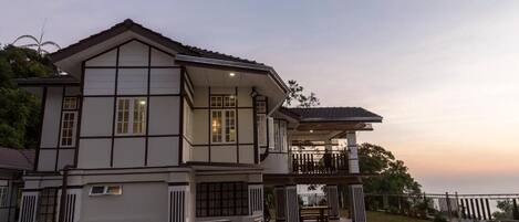 A large, two-story building with a balcony and a covered outdoor seating area.