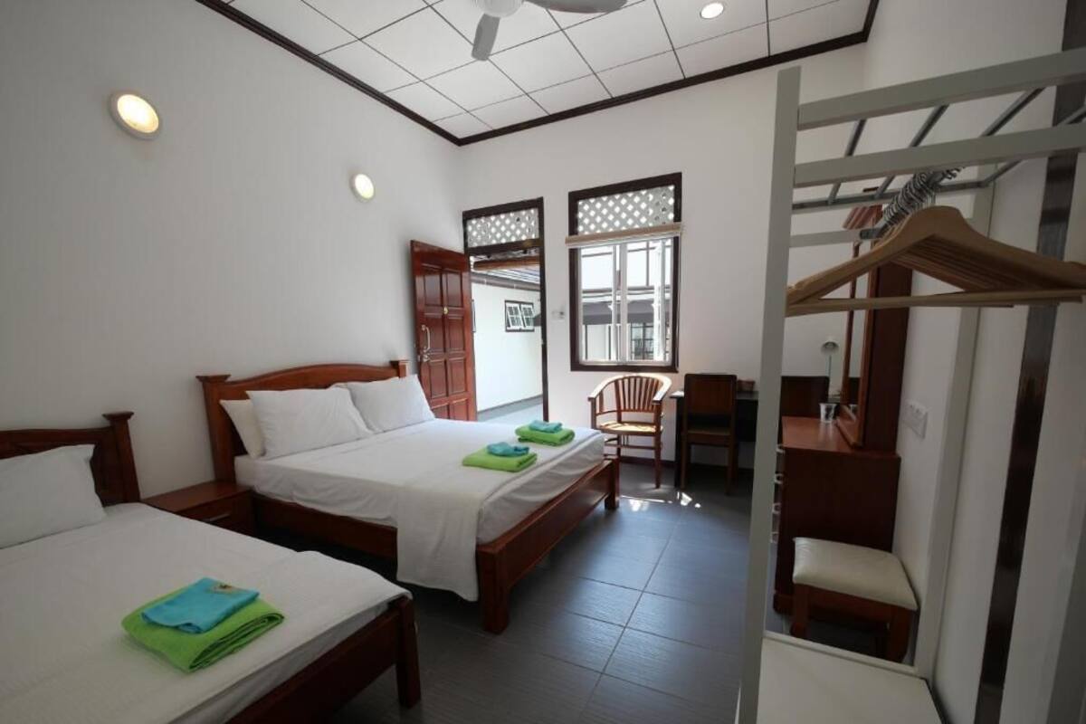 Une chambre d’hôtel avec deux lits, un bureau, une chaise, une armoire et une fenêtre donnant sur un paysage agréable.
