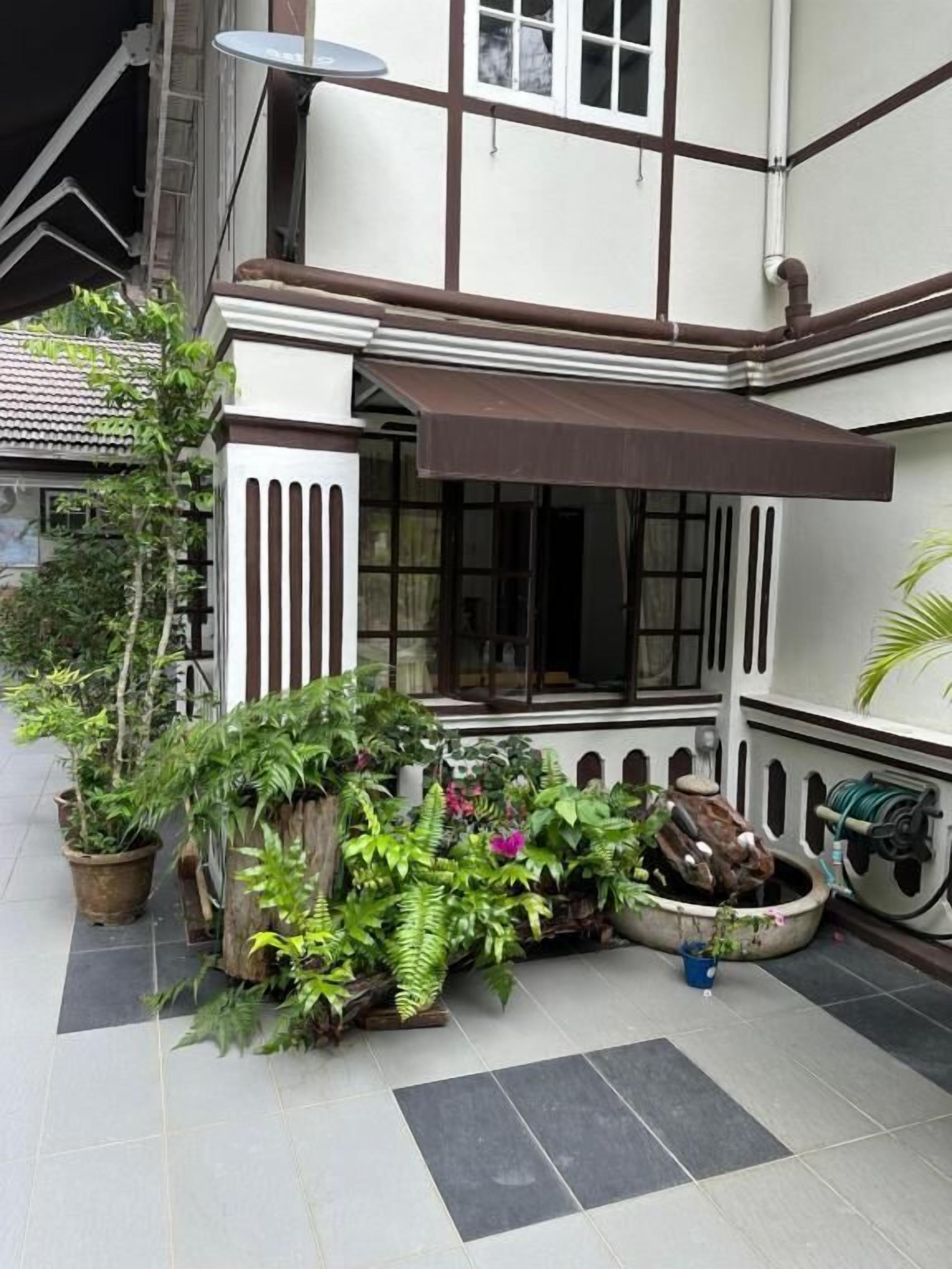 A building with a covered entrance, potted plants, and a water feature.