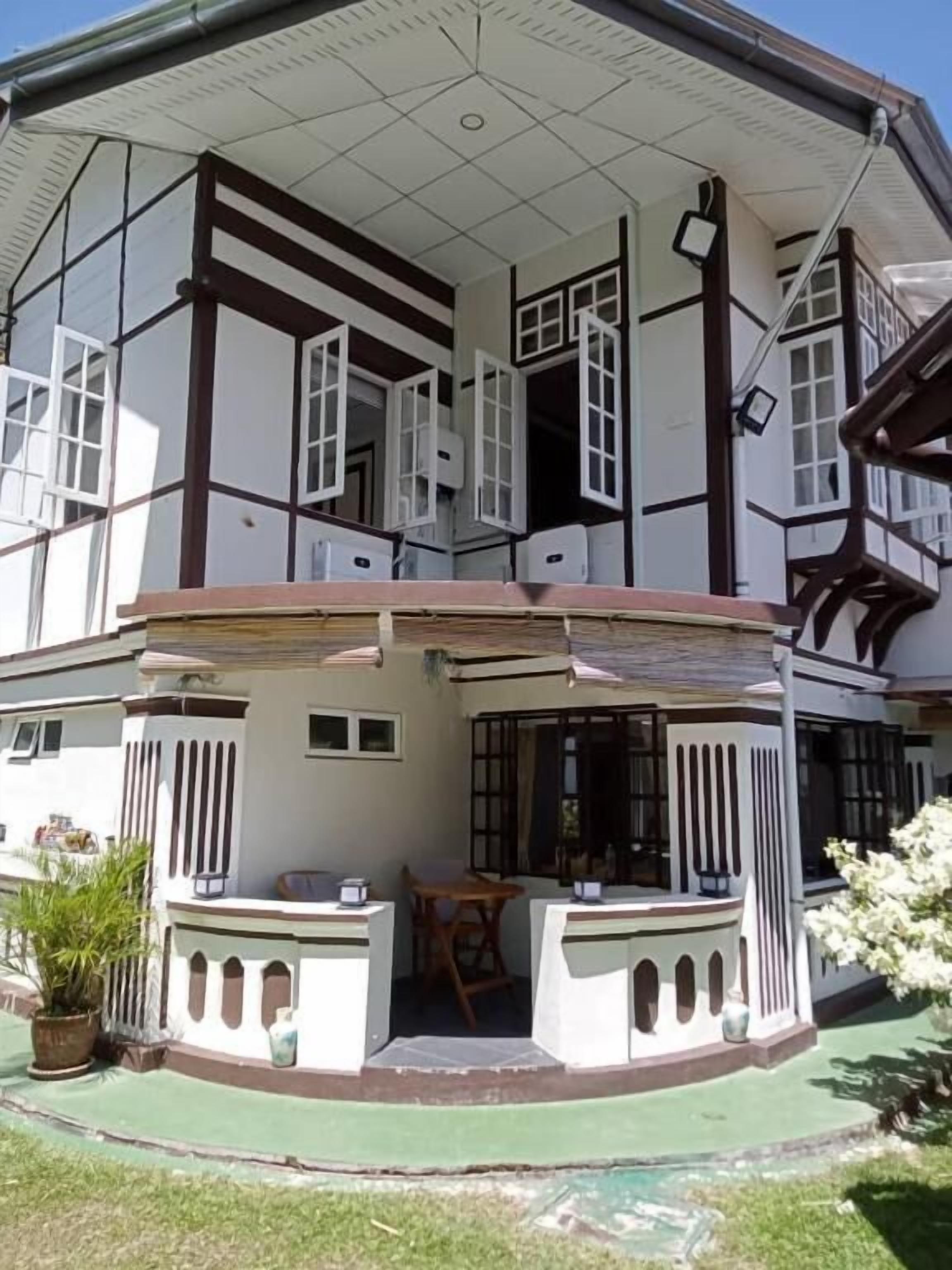 A two-story building with a balcony, a covered patio, and a small outdoor seating area.