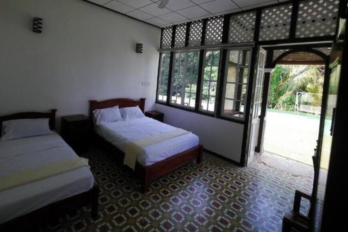 Une chambre avec deux lits, un sol à motifs et une vue sur la verdure.
