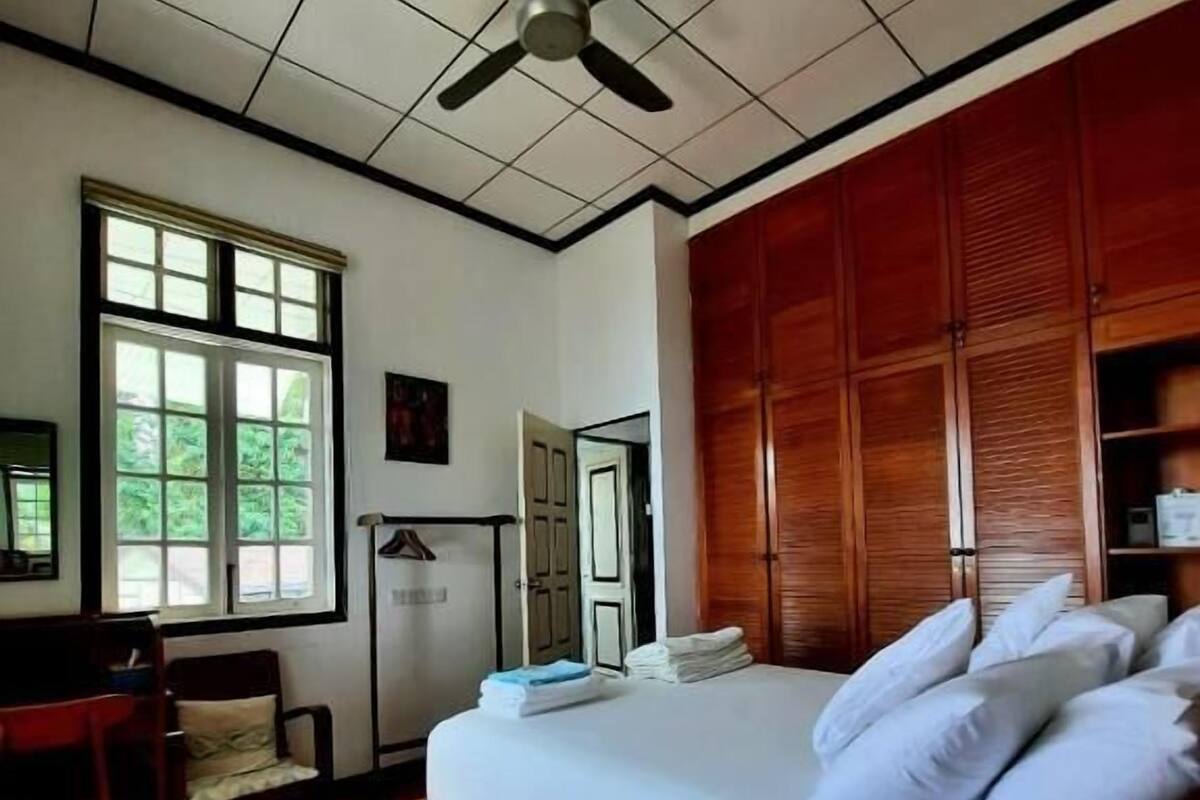 Une chambre à coucher avec un lit, un ventilateur de plafond, un bureau et une fenêtre.