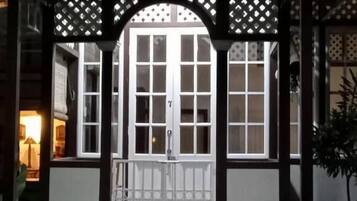 A covered entrance with a wooden archway, a white door with a number, and steps leading up to it.