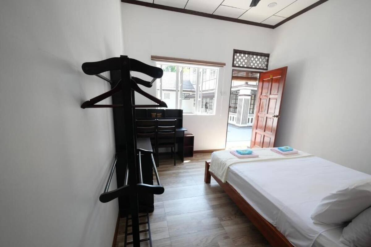 Une chambre à coucher avec un lit, un bureau, une chaise, une armoire et une fenêtre.
