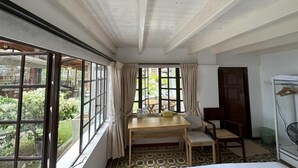 A room with a wooden table, two chairs, a bed, a window with curtains, and a door. - Hickory Penang Hill (George Town)