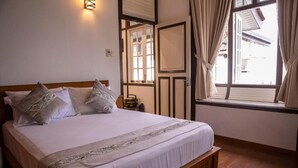 A bedroom with a bed, a nightstand, a window with curtains, and a wall-mounted light fixture. - Hickory Penang Hill (George Town)