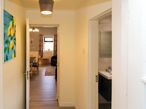 A hallway leading to a dining area with a table and chairs, a window with curtains, and a door to a kitchen area. - THADG AND HANNAH’S, pet friendly in Killorglin, County Kerry (Milltown)