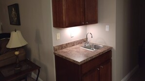 Una pequeña cocina con armarios de madera, encimera de granito y un fregadero.