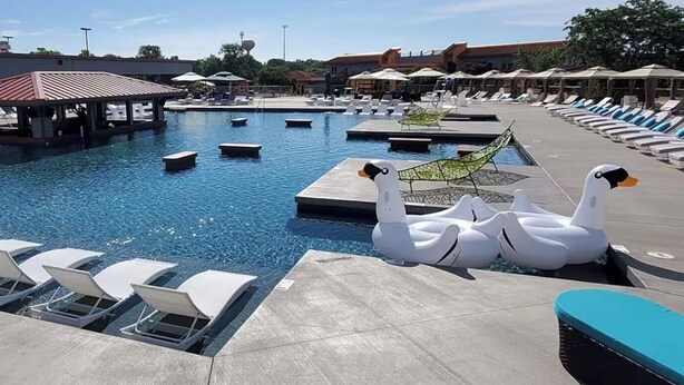 Una piscina con sillas de descanso, un flotador con forma de pato y una zona techada.