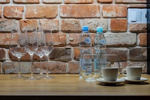 Ein Tisch mit Weingläsern, Wasserflaschen und Tassen vor einer Ziegelwand.