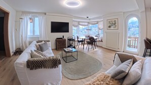 Een ruime woonkamer met een bank, salontafel en een eettafel.