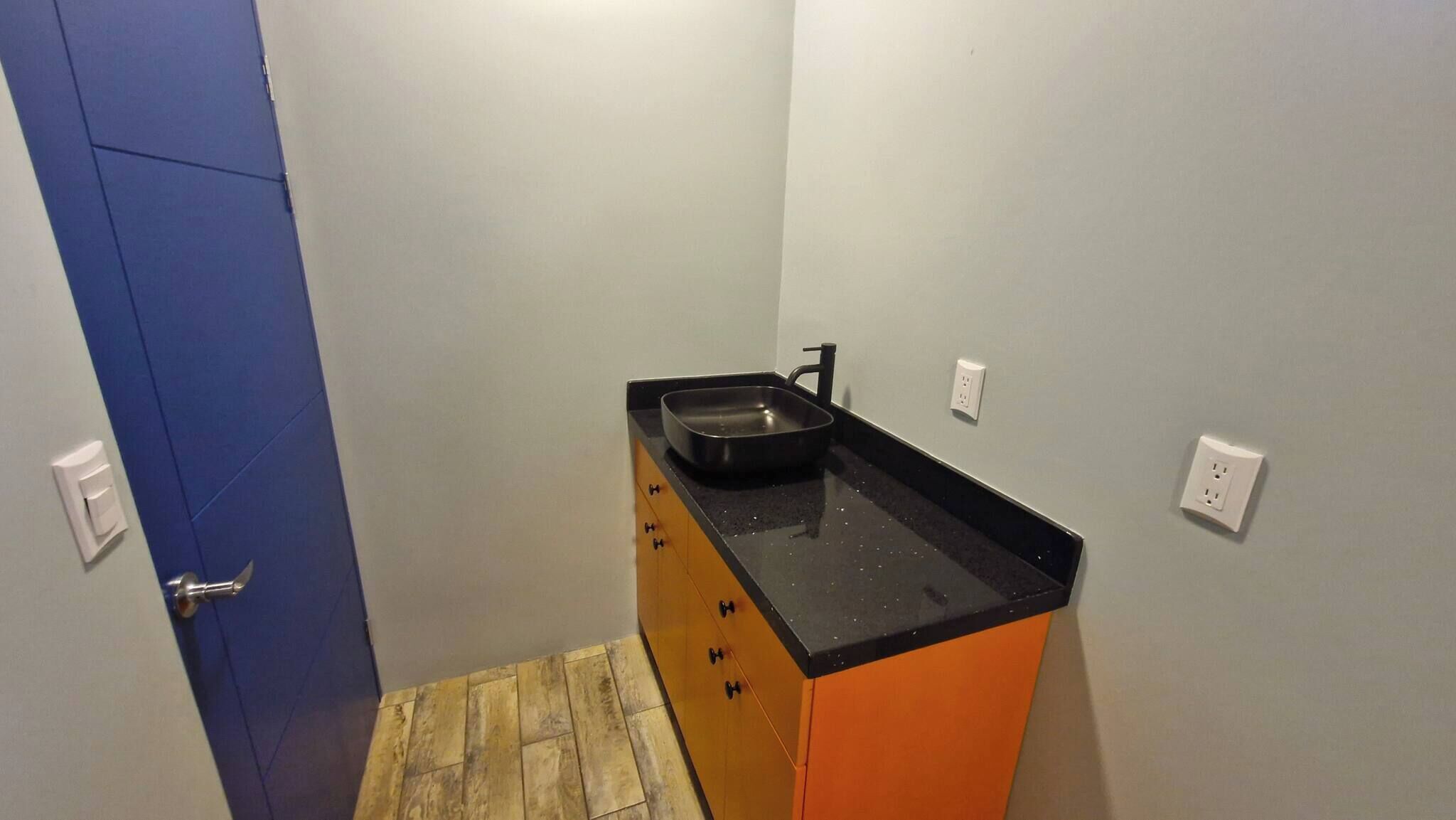 A small kitchen with a black countertop, a sink, and wooden cabinets.