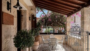 A covered outdoor seating area with stone walls, a tiled floor, and a wrought iron gate. - Kissamos Villa in Crete Island (Kissamos)