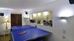 A room with a ping pong table, a wooden door, a lamp, and a wall-mounted clock. - Kissamos Villa in Crete Island (Kissamos)