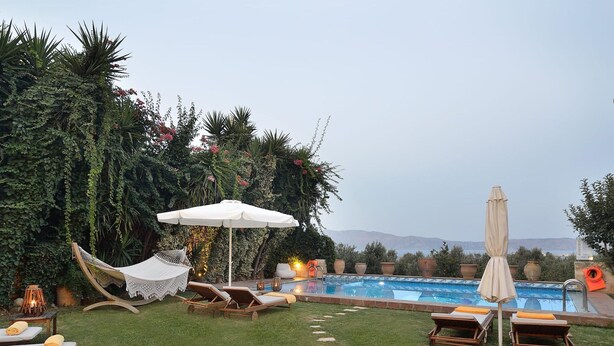 A poolside area with lounge chairs, a hammock, and a view of the mountains. - Kissamos Villa in Crete Island (Kissamos)