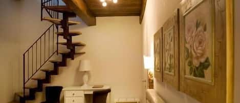 Une chambre avec un lit, un bureau, une chaise, un escalier et des œuvres d’art murales.