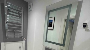 Un baño moderno con inodoro, bidé y un espejo con un cuadro enmarcado.