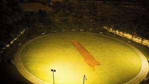 Un terrain de sport circulaire avec une piste centrale, entouré d’une promenade dallée et bordé de bancs sur tout le pourtour.