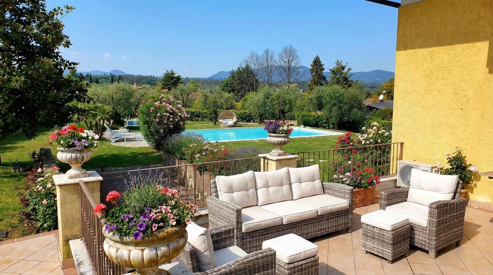 A patio with wicker furniture, a pool, and a view of mountains.