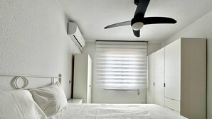 A bedroom with a bed, a ceiling fan, an air conditioning unit, a window with blinds, and a wardrobe. - Apartment With Pool and Golf Course Views in Roquetas de Mar (Roquetas de Mar)
