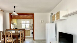 A modern kitchen with a dining area, a TV, and a washing machine. - Apartment With Pool and Golf Course Views in Roquetas de Mar (Roquetas de Mar)