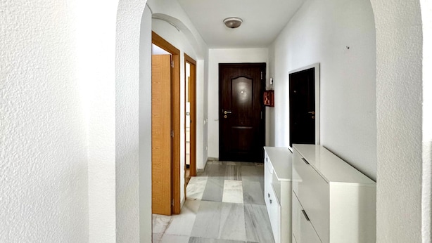 A hallway with a white wall, a wooden door, a dark wooden door, and a white cabinet. - Apartment With Pool and Golf Course Views in Roquetas de Mar (Roquetas de Mar)