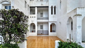 A courtyard with a tiled floor, white walls, and a tree. - Apartment With Pool and Golf Course Views in Roquetas de Mar (Roquetas de Mar)