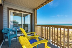 En balkon med udsigt over stranden, et bord og to stole.